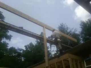 Carpenter setting a ridge beam over a new addition frame — Ice Dam Removal by Roofing Brothers in Knights Landing