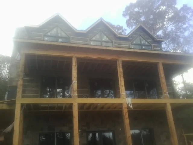 Dormers and porch framing on a large log home under construction — Roof Coating work by our crew in Knights Landing