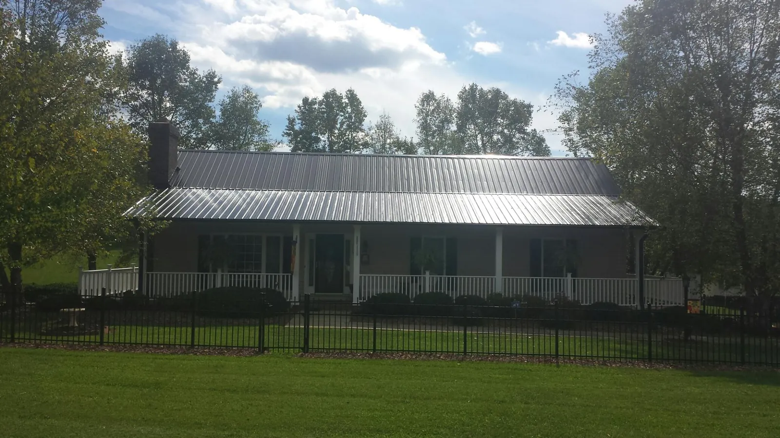 Gray metal roof on a brick ranch with a full width front porch — Gutter Guard Installation work by our crew in Knights Landing