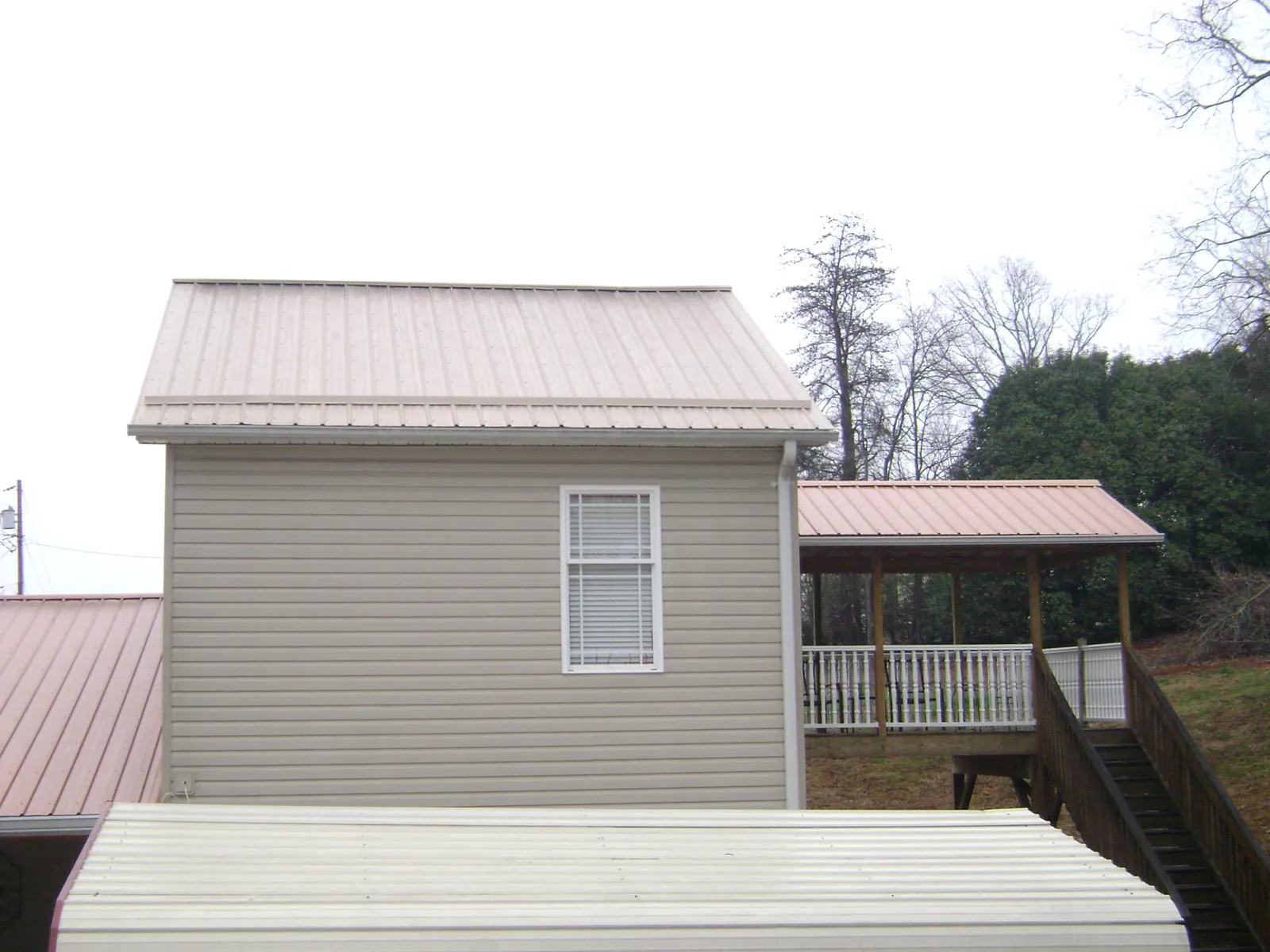 Tan metal roofs on a two story addition and attached porch, from a Roof Replacement job in Knights Landing