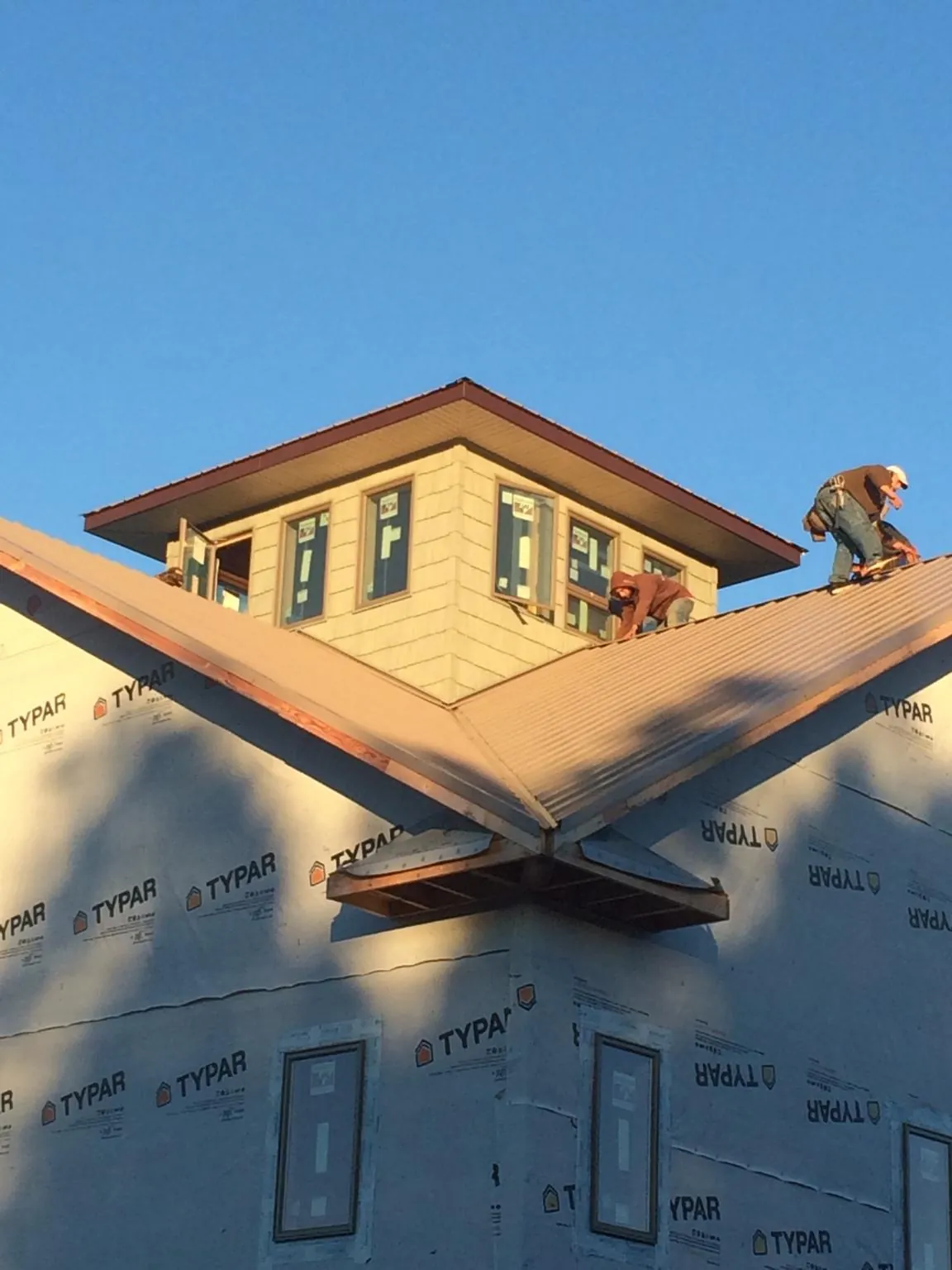Roofers working around a rooftop cupola on a new metal roof at sunset — Roof Waterproofing in Knights Landing by Roofing Brothers